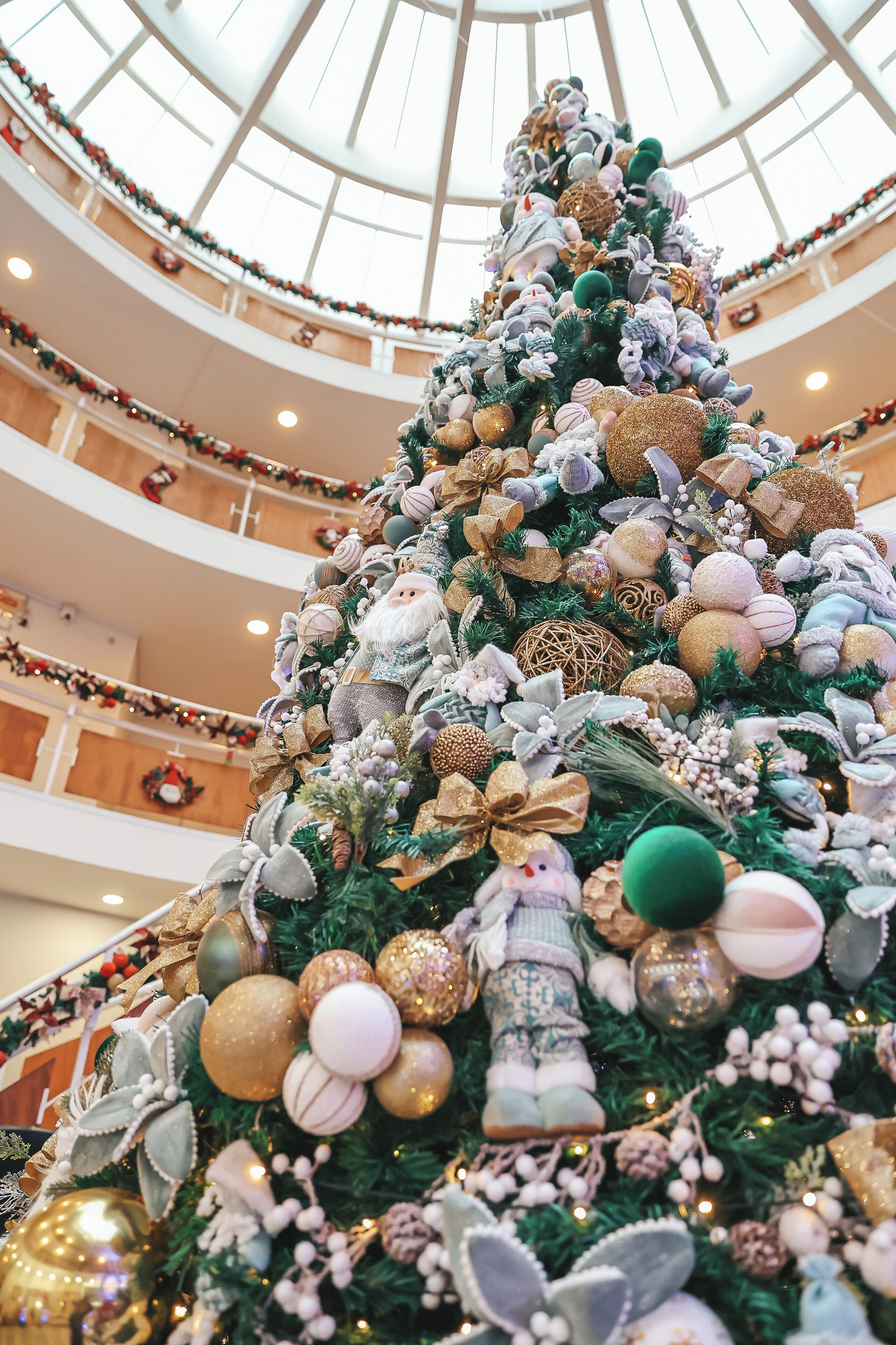 Un atrium à plusieurs niveaux, orné d’un grand sapin de Noël richement décoré.