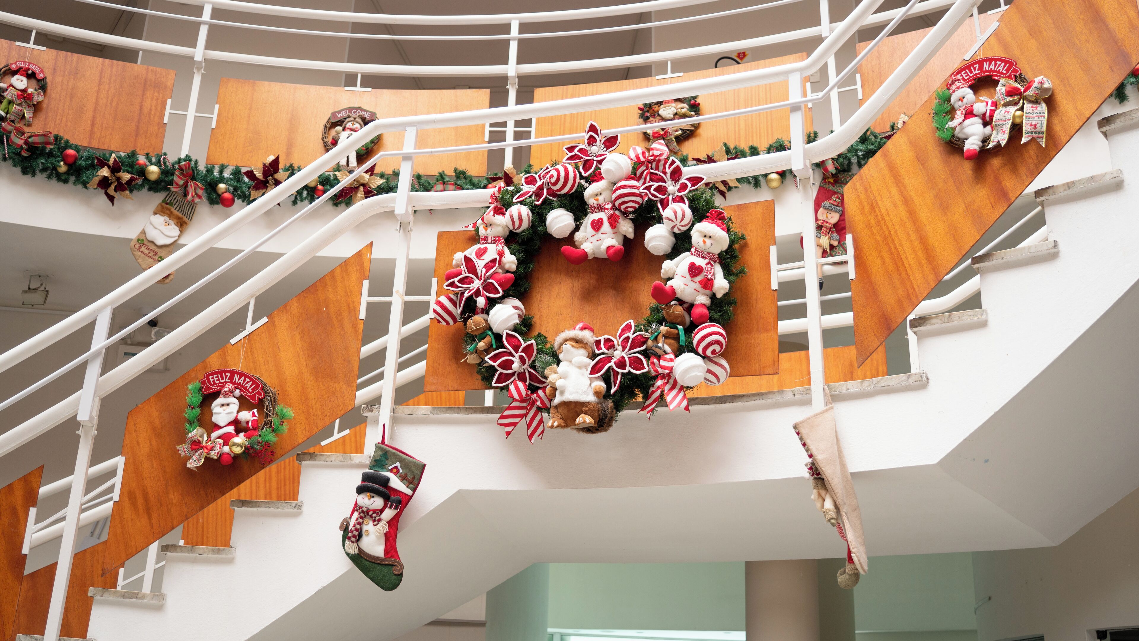A multi-level interior with Christmas decorations, including wreaths and stockings, and a wooden staircase.