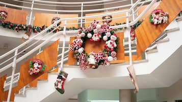 A multi-level interior with Christmas decorations, including wreaths and stockings, and a wooden staircase.