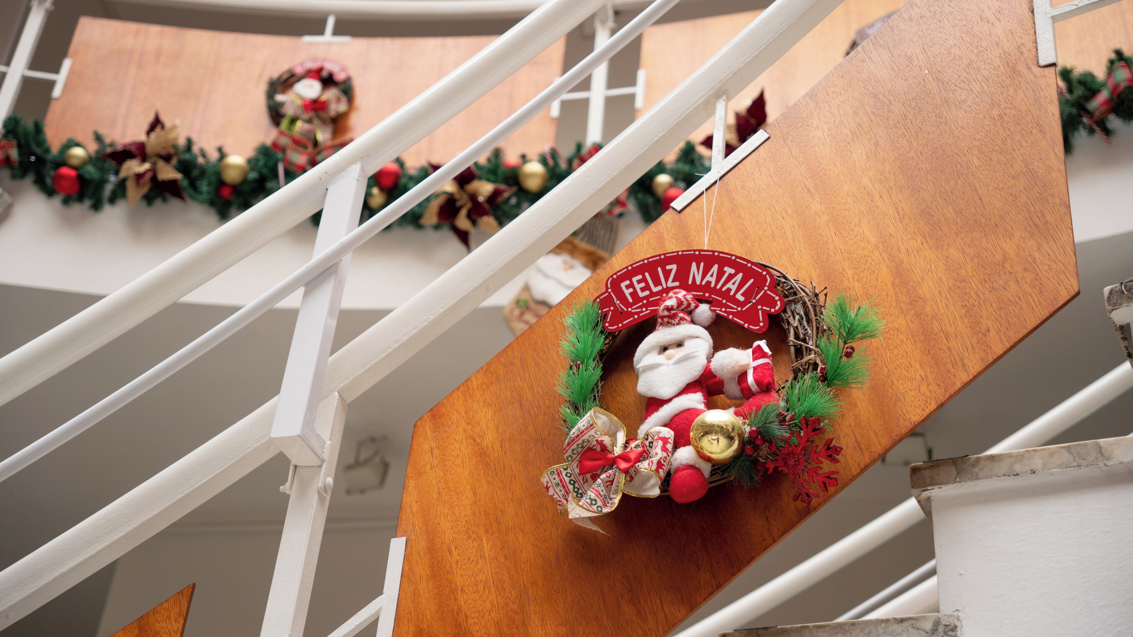 A staircase with a festive wreath and a sign that reads "FELIZ NATAL".
