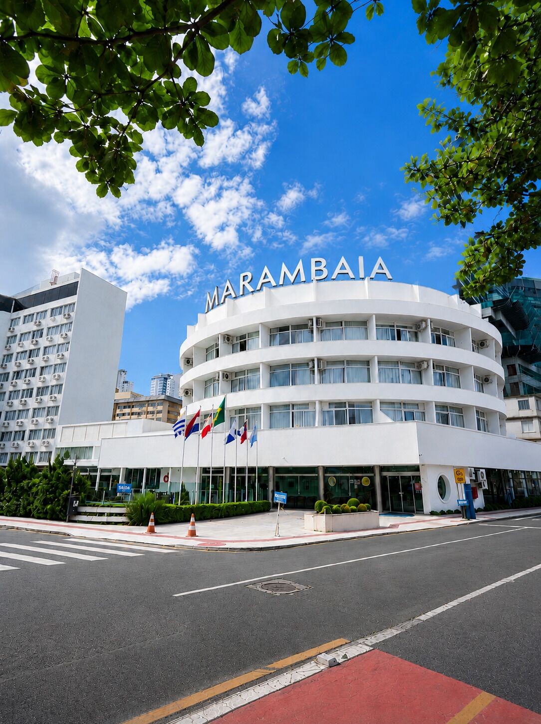 Un hotel moderno con fachada circular, varias banderas y cielo despejado.