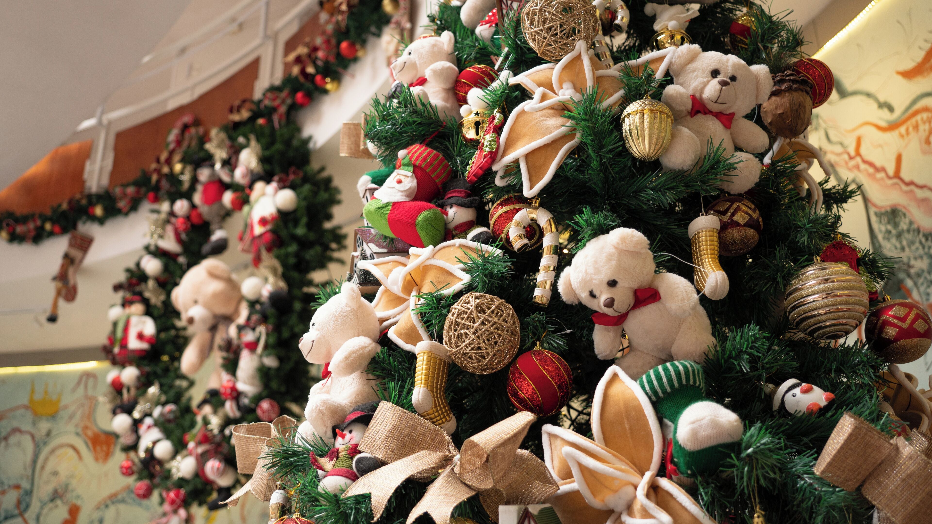 A Christmas tree decorated with teddy bears, ornaments, and ribbons.