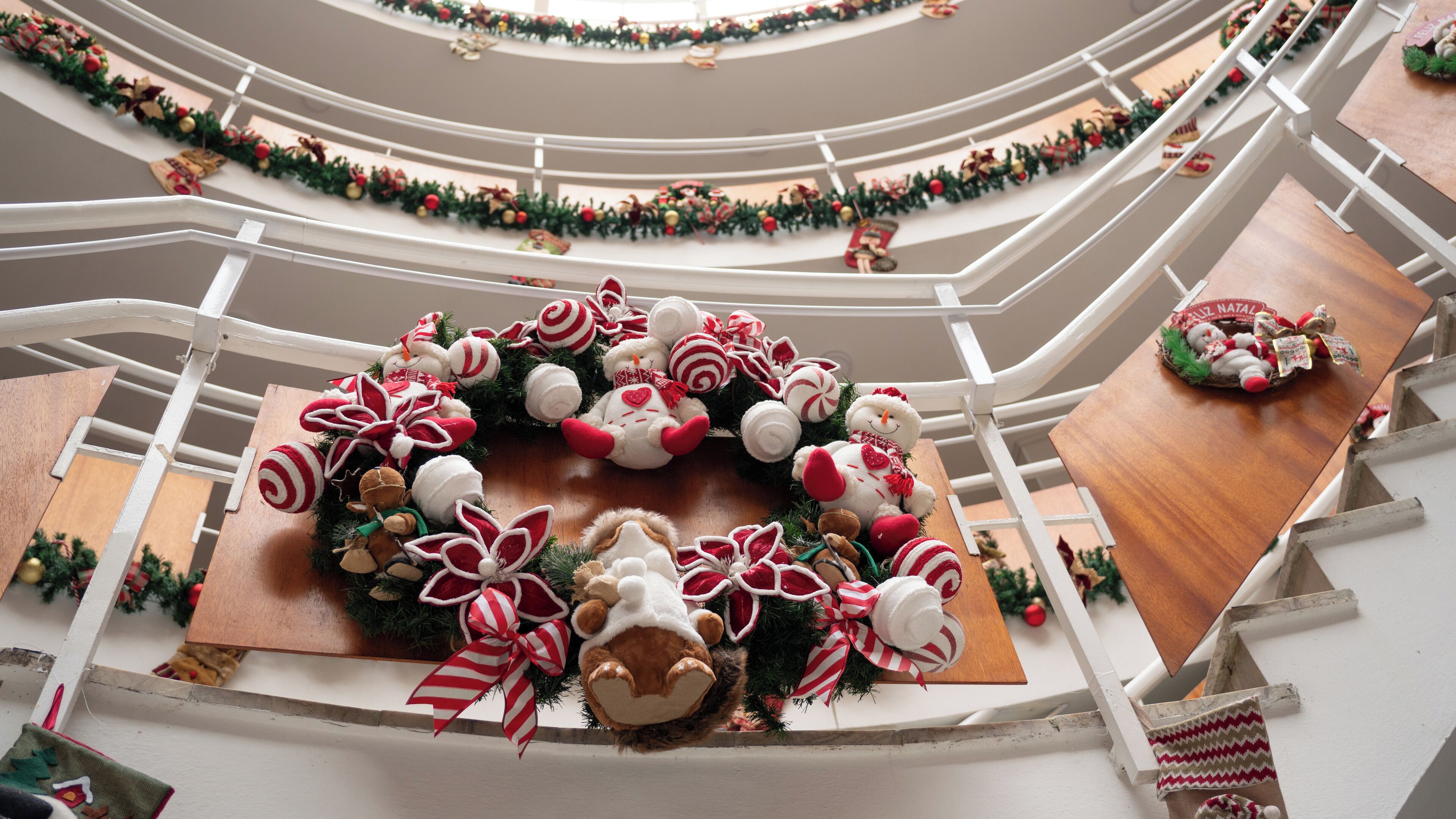 Een meerlaags atrium, versierd met kerstkransen en zachte knuffels.
