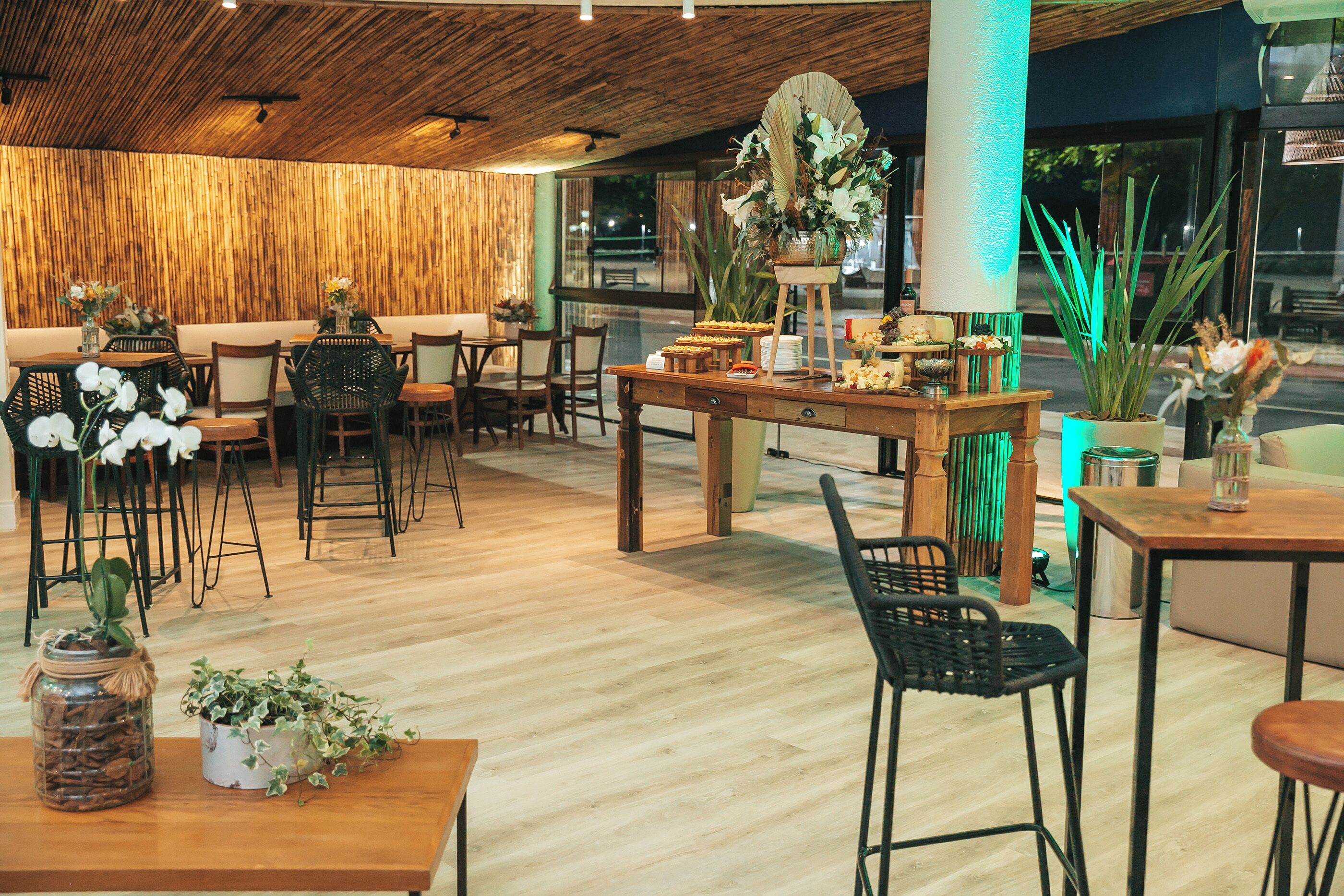 Un restaurant doté d’un plancher en bois, de chaises noires et de tables ornées de centres de table floraux.
