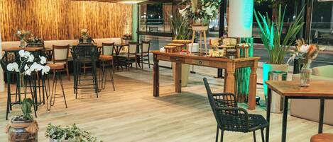 Un restaurant doté d’un plancher en bois, de chaises noires et de tables ornées de centres de table floraux.