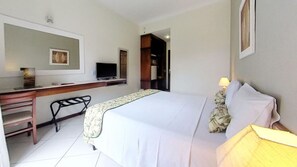 A hotel room with a bed, a desk, a chair, a television, and a lamp. - Hotel Ilhas Do Caribe (Guarujá)