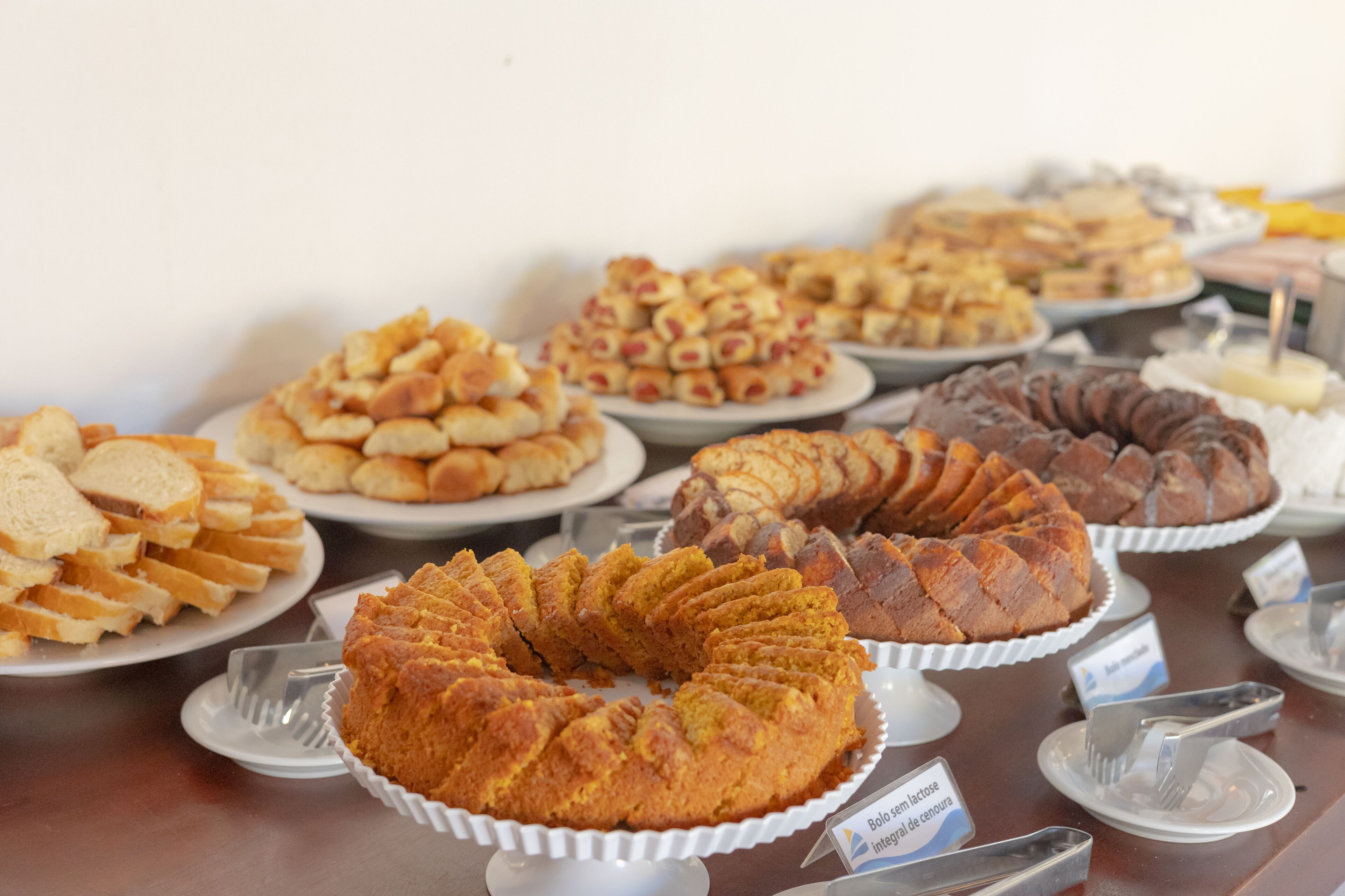 A buffet table with various baked goods including bread, muffins, and a bundt cake.