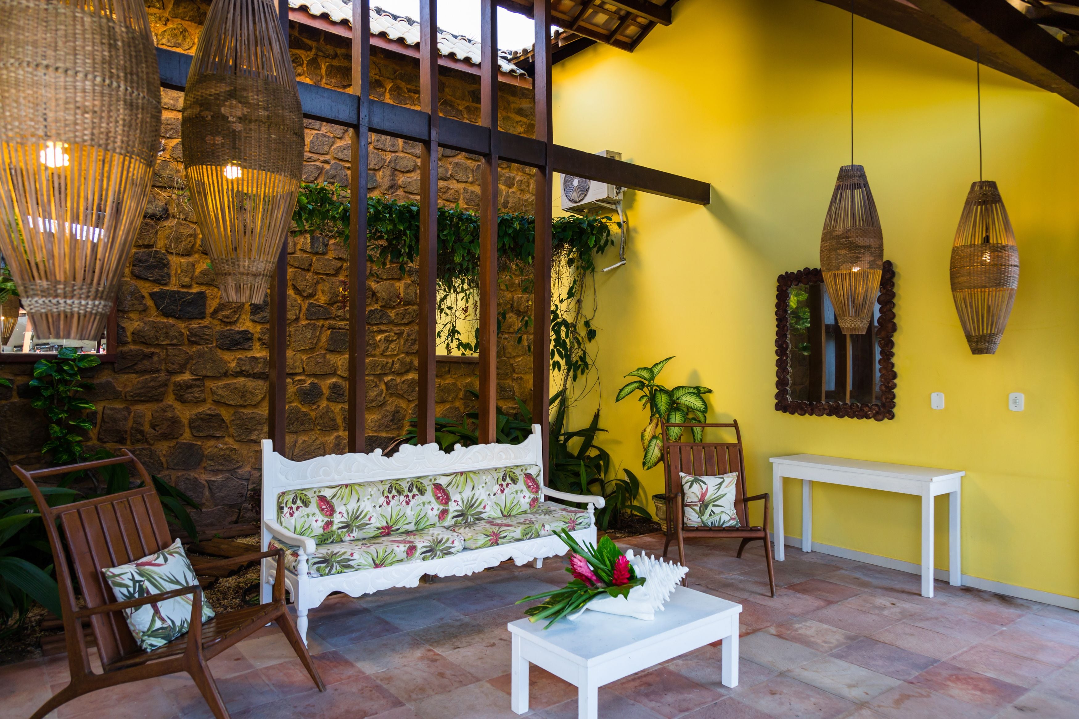A cozy seating area with a stone wall, wicker lamps, and a yellow wall.