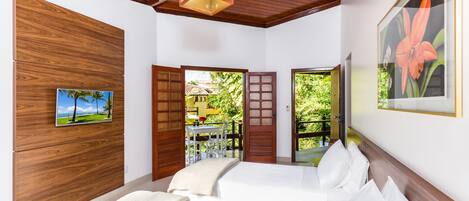 A hotel room with a wooden ceiling, a bed with white linens, a wooden wall panel, and a framed picture of a flower.