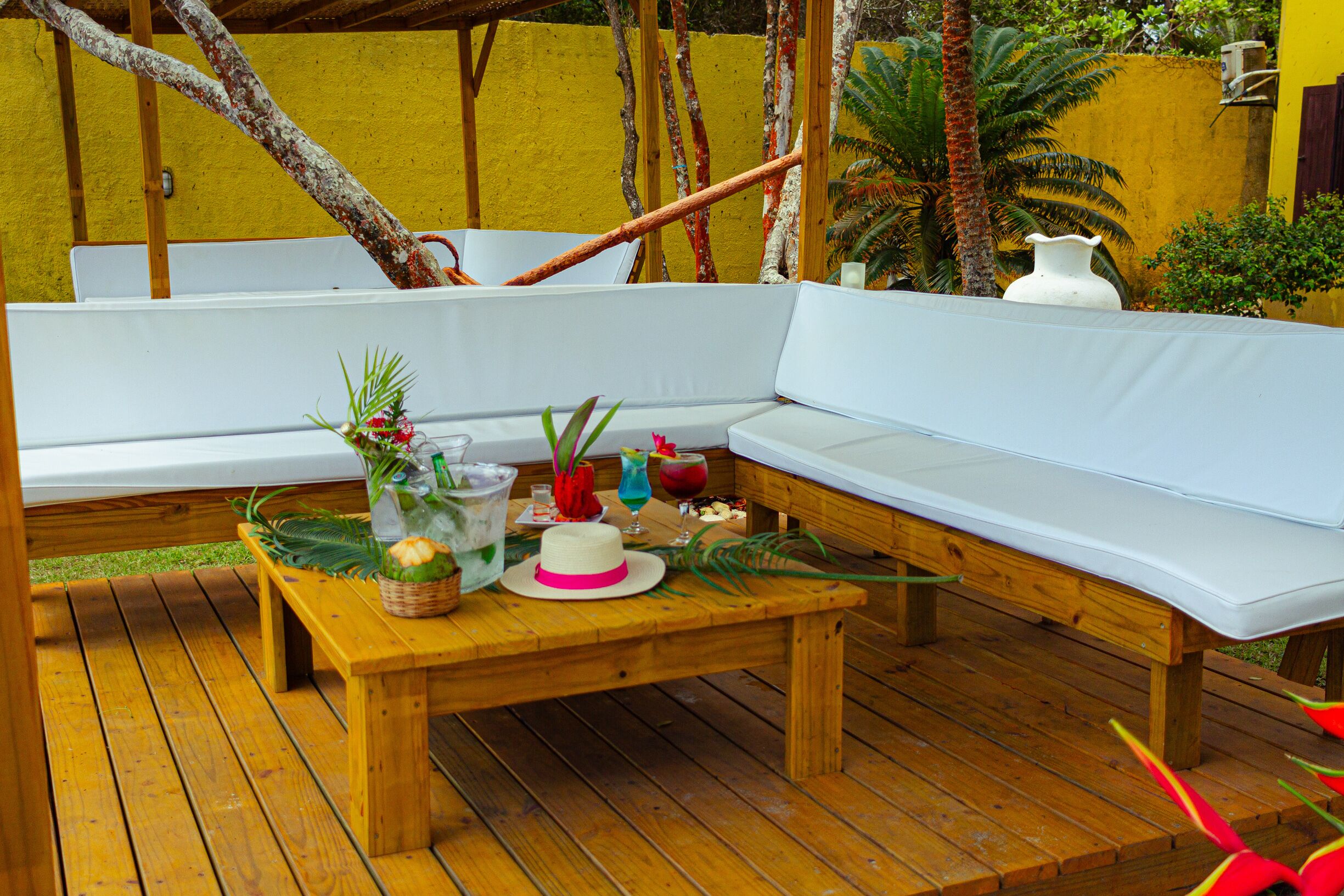Una terraza de madera con un sofá blanco y una mesa de madera con diversos objetos.