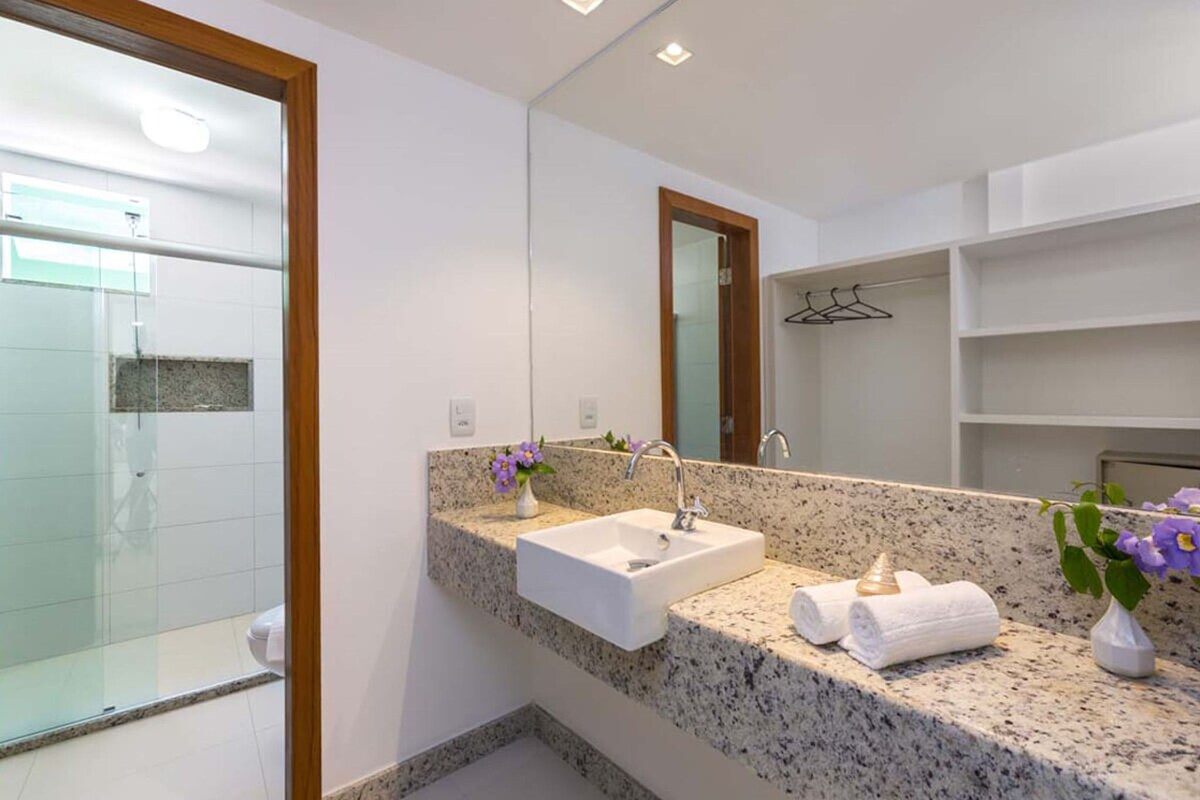 A modern bathroom with a granite countertop, a white sink, and a large mirror.