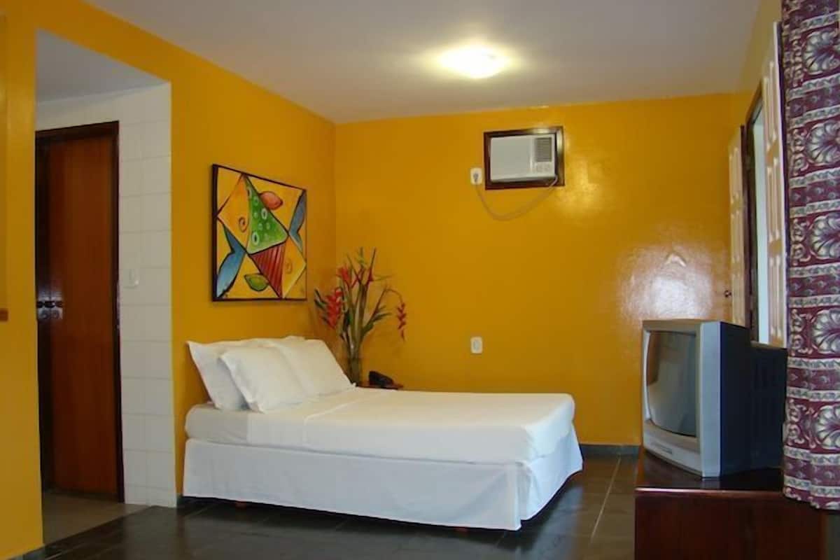 A room with a bed, a television, and a painting on the wall.