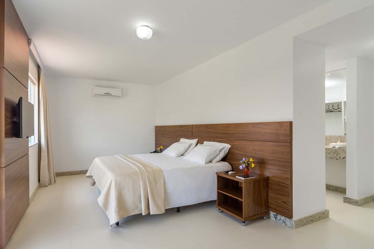 A bedroom with a bed, bedside tables, a TV, and a ceiling light.