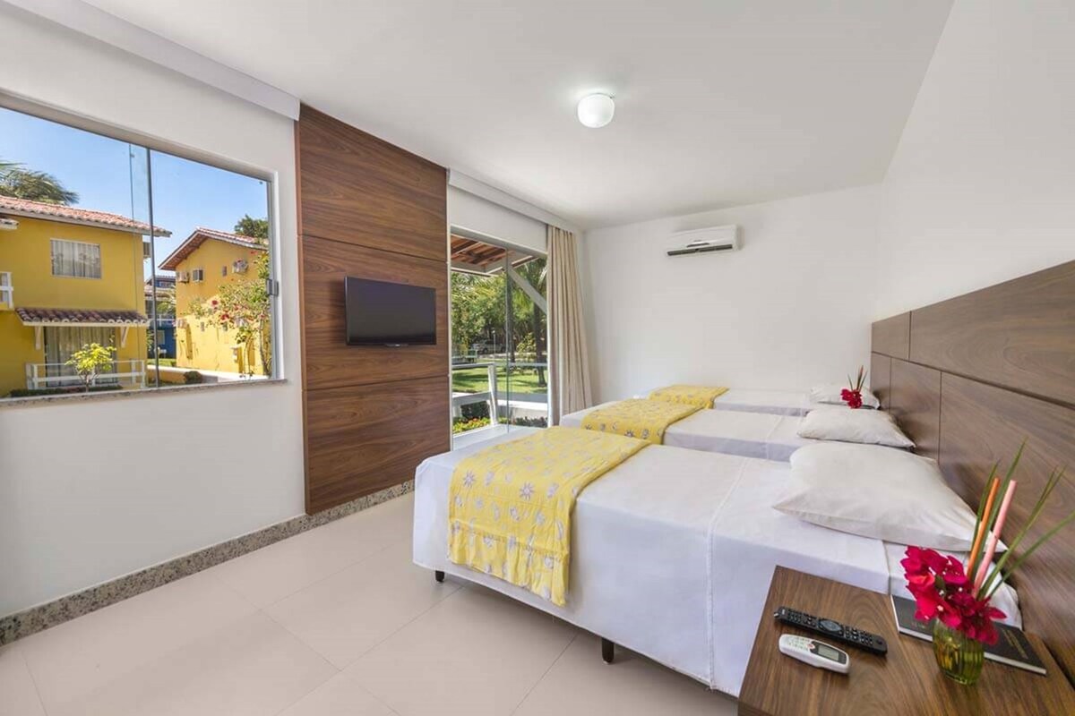 A hotel room with a bed, a TV, and a view of the outside.