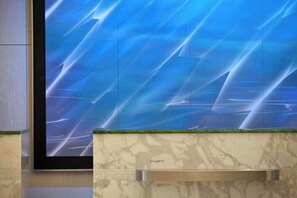 A modern interior with a large digital display on the wall, marble countertops, and a metallic handle. - Renaissance Arlington Capital View Hotel (Arlington)