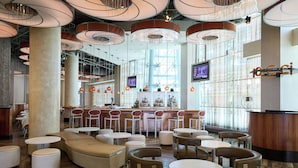 A modern bar area with round tables, cushioned seating, and a bar counter.