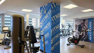 A gym with exercise equipment, a large blue wall with 'Fitness on Demand' branding, and a poster of a cyclist.