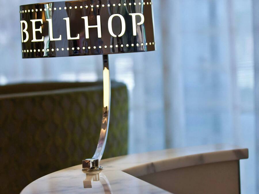 A sign with the word "BELLHOP" on a metal stand, placed on a round table with a patterned base.