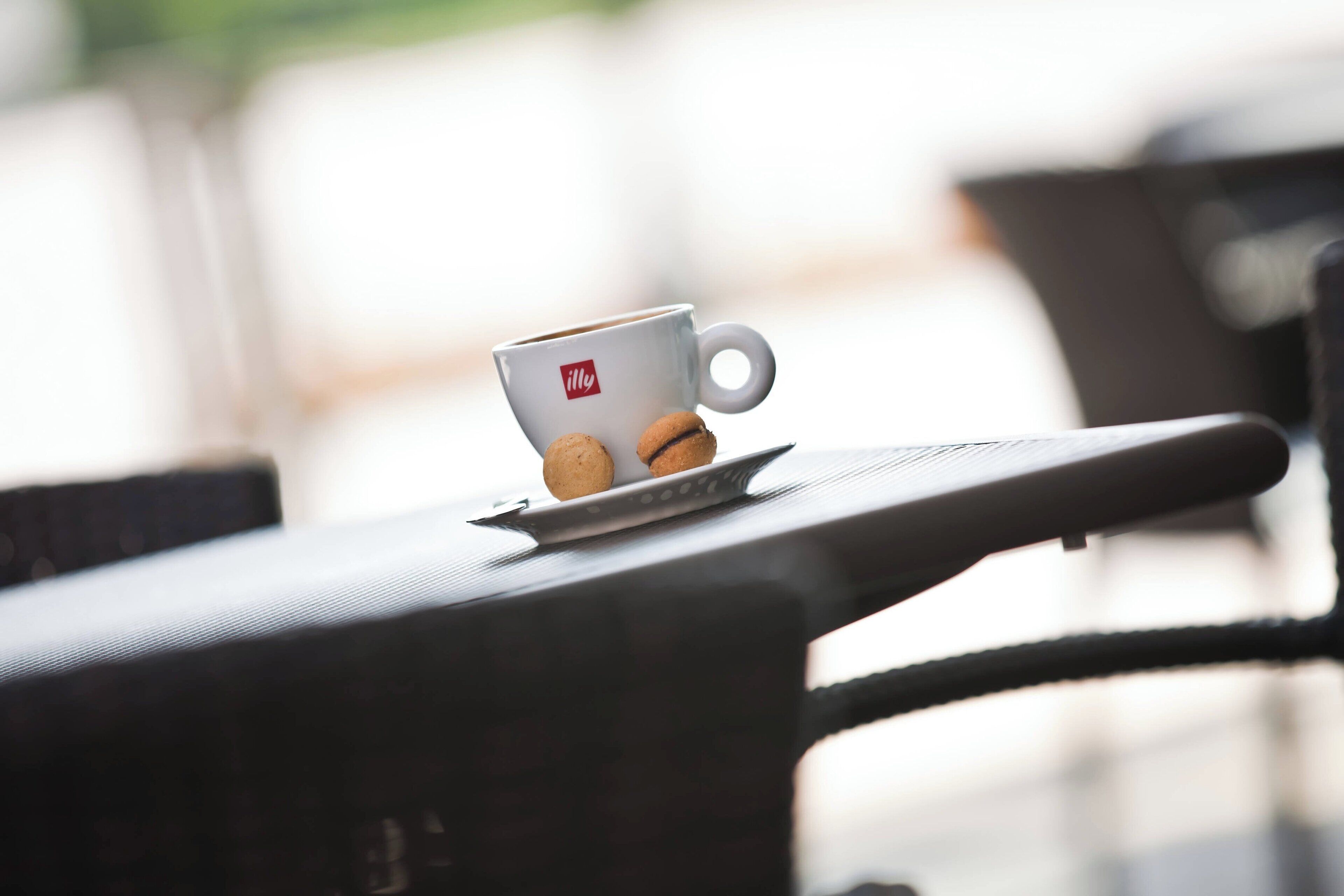 A white cup with a logo on a table, accompanied by two cookies.