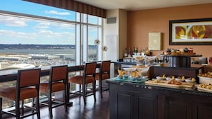 A modern kitchen with a large island, bar stools, and a view of an airport.