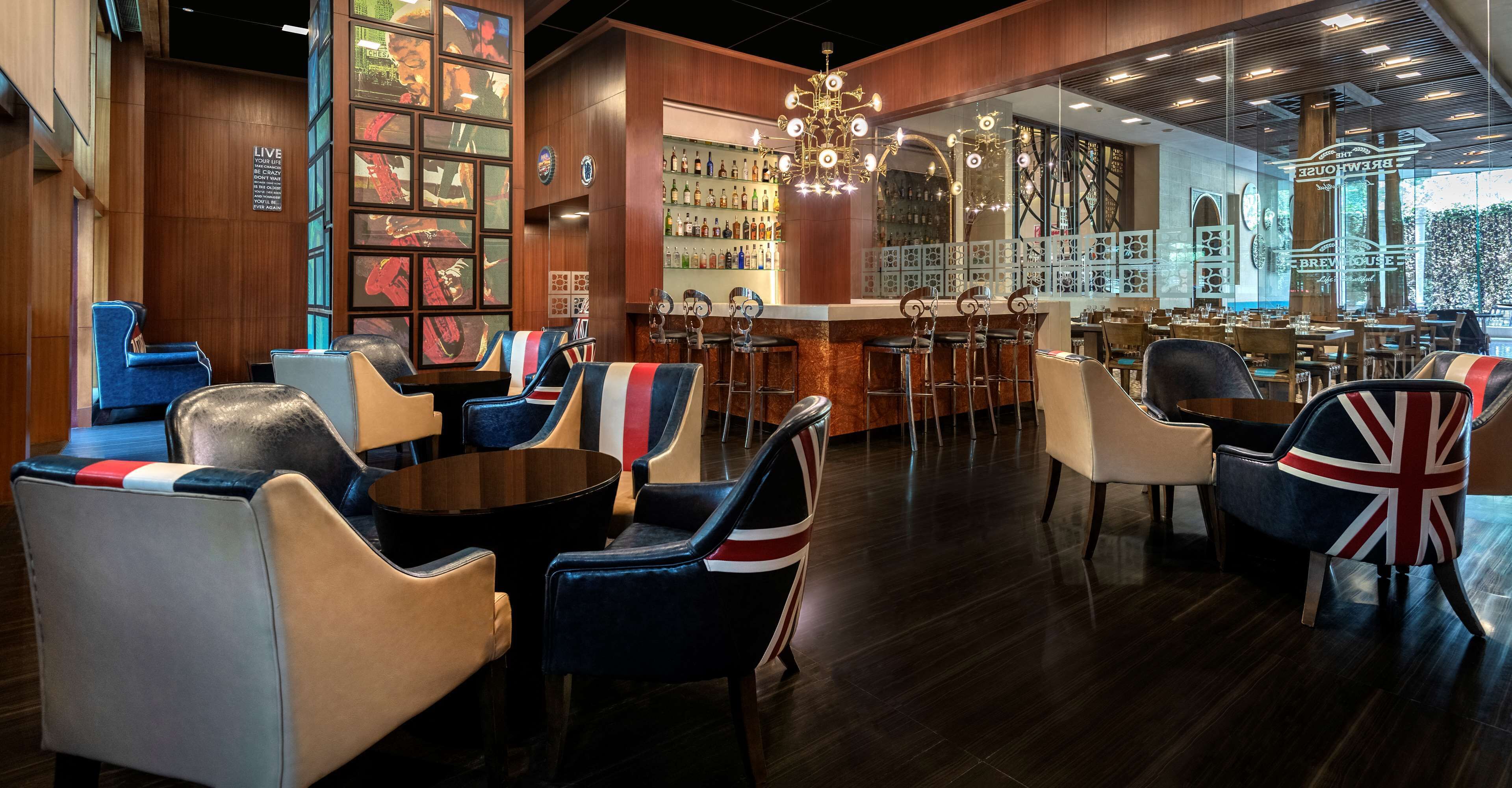 A bar area with multiple seating options, including bar stools and chairs, and a variety of bottles on shelves.