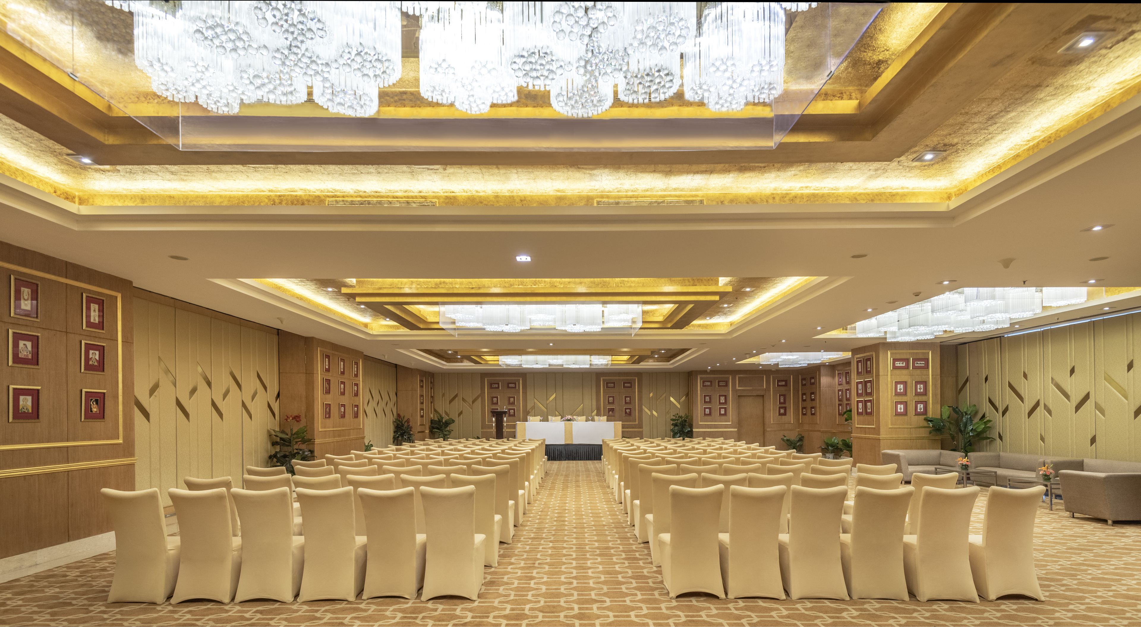 Une salle de conférence spacieuse, avec des rangées de chaises, un pupitre et un grand lustre.