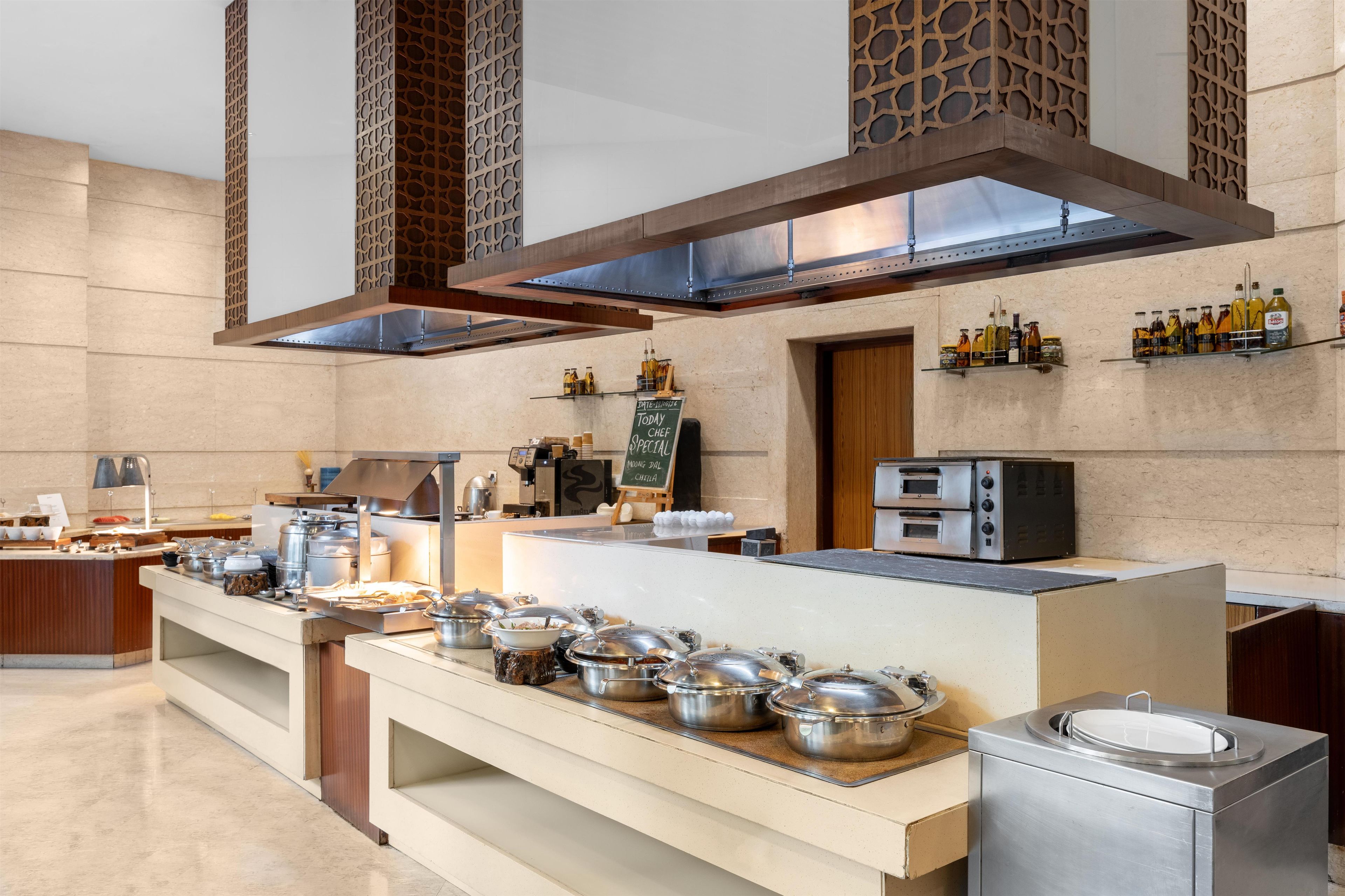 A modern kitchen with stainless steel appliances, a buffet setup, and a chalkboard menu.