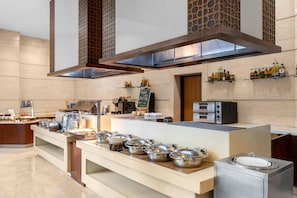 A modern kitchen with stainless steel appliances, a buffet setup, and a chalkboard menu. - Radisson Gurugram Sohna Road City Center (Gurugram)