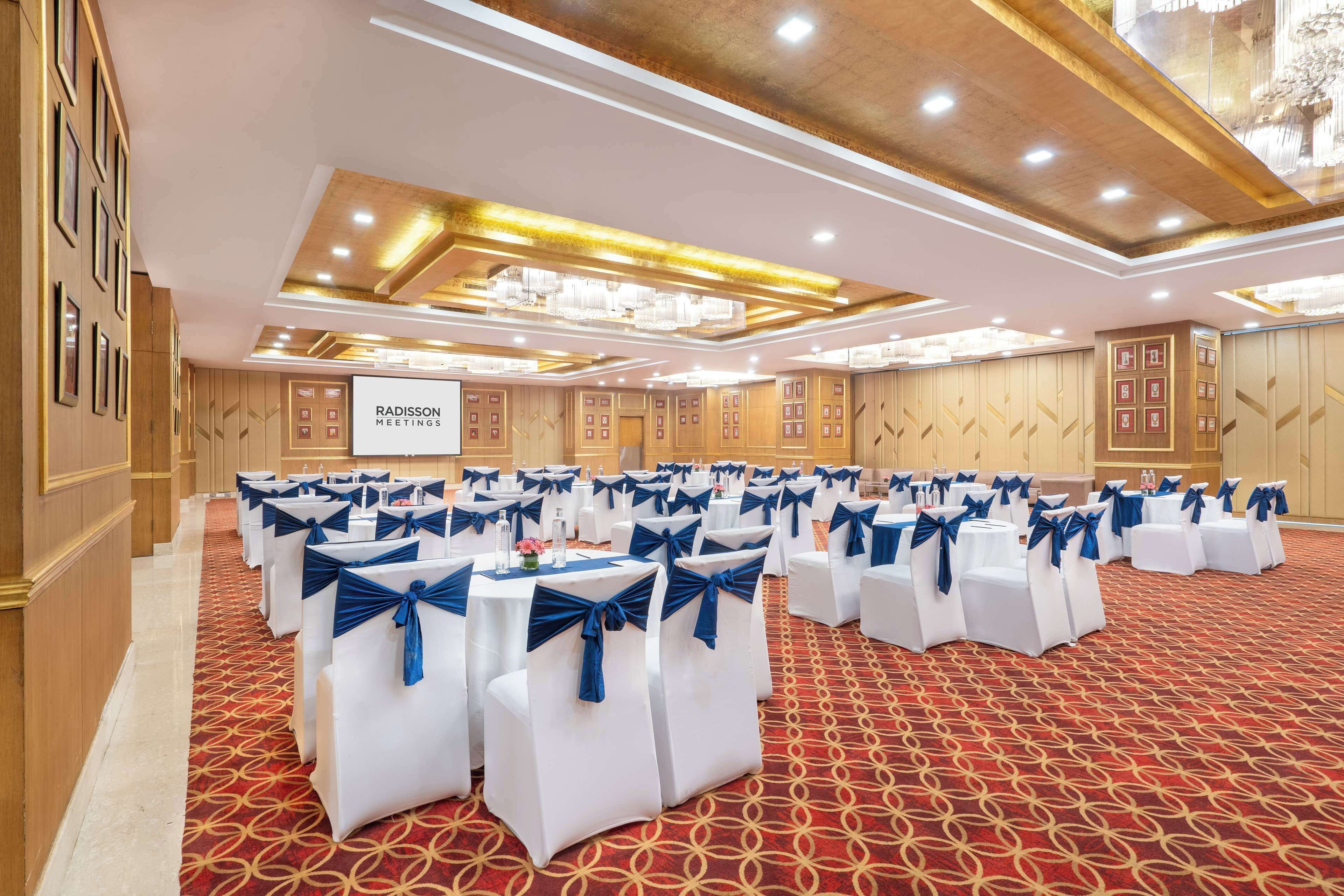 A conference room with rows of tables and chairs, a red patterned carpet, and a sign reading "Radisson Meetings".