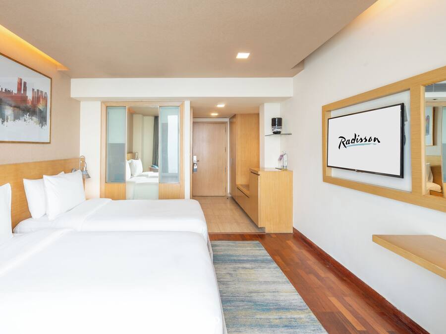 Habitación de hotel con una cama grande, un escritorio, un espejo y una pintura de un paisaje urbano.