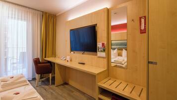 Habitación de hotel con escritorio, silla, televisor y cama con toallas.