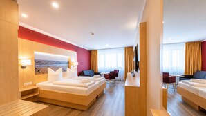 A hotel room with a large bed, a desk, a chair, a TV, and a window with curtains. - Hotel an der Stadthalle Rostock-Hbf (Rostock)