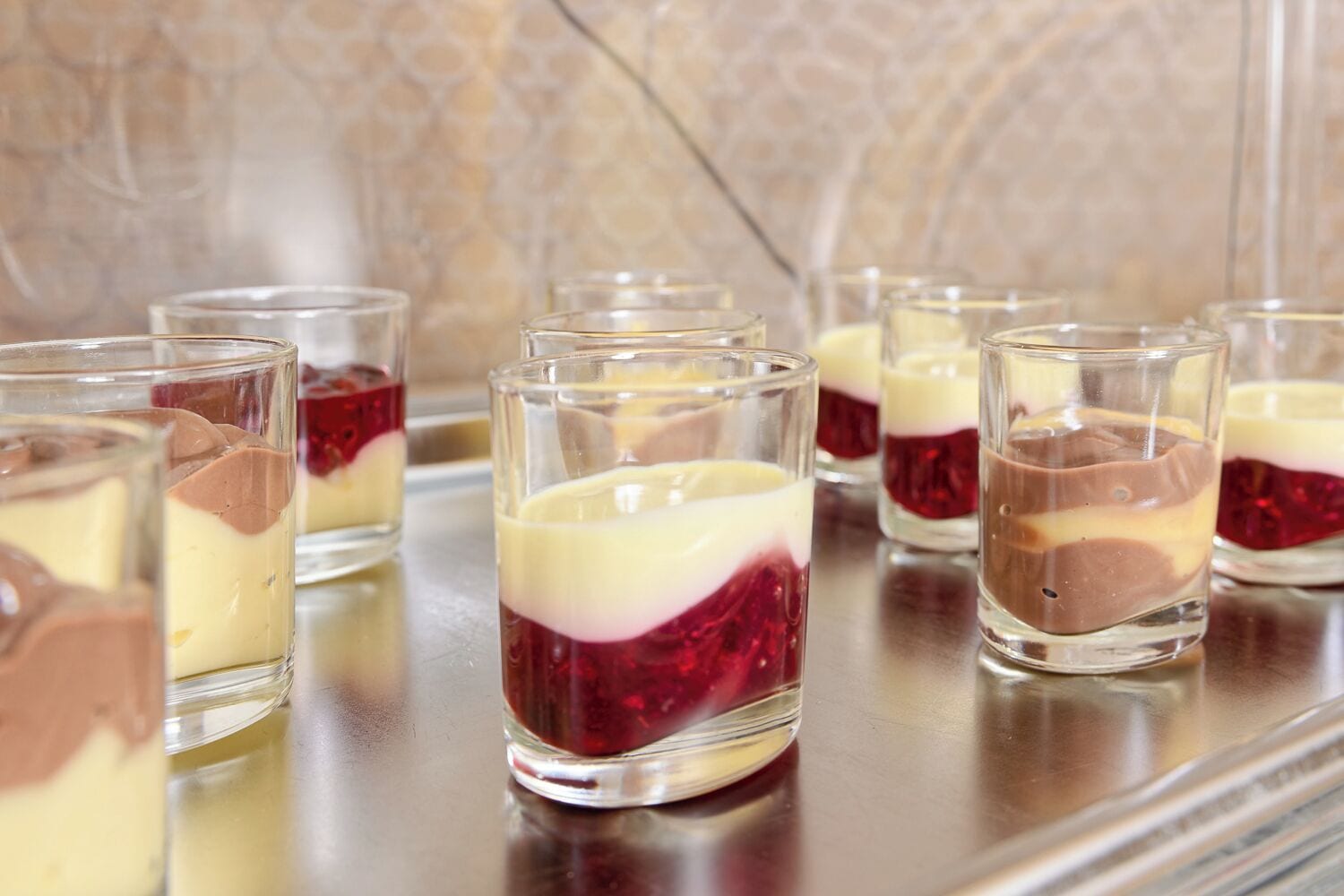 A dessert tray with layered desserts in clear glasses.