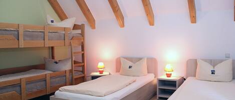 A room with two beds, a bunk bed, and a nightstand with a lamp.