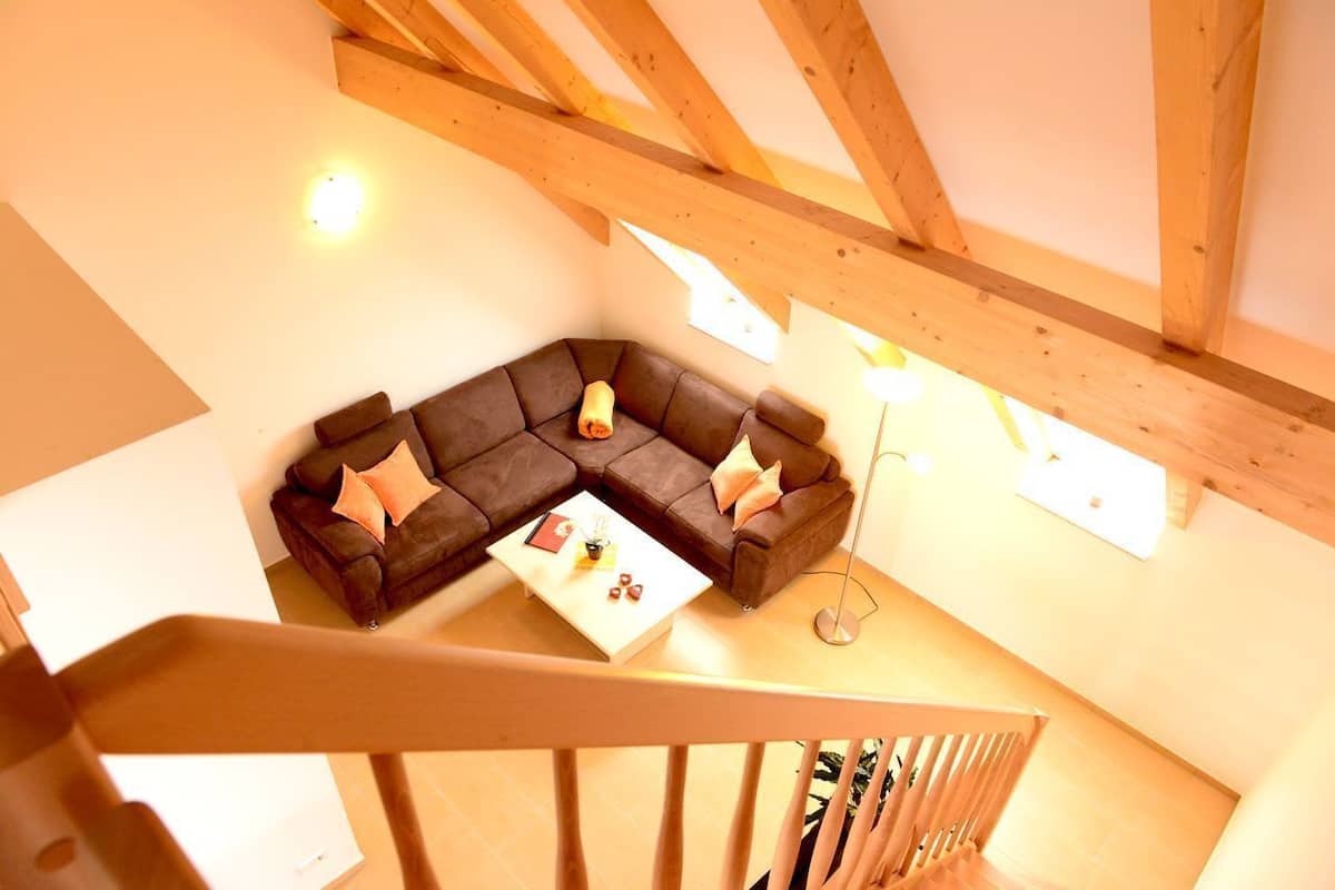 Uma sala de estar aconchegante no estilo loft, com um sofá seccional, uma mesa de centro e uma escada.