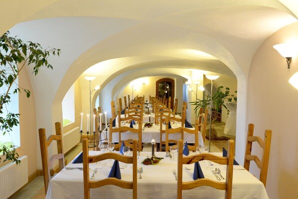 A long dining table with chairs, candles, and table settings in a room with arched ceilings and a plant. - Weichaer Hof - Apartments (Weissenberg)