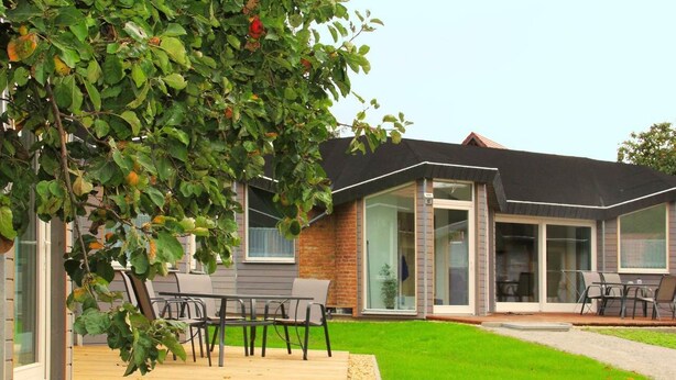 A modern house with a patio, a dining area, and a covered outdoor seating area.