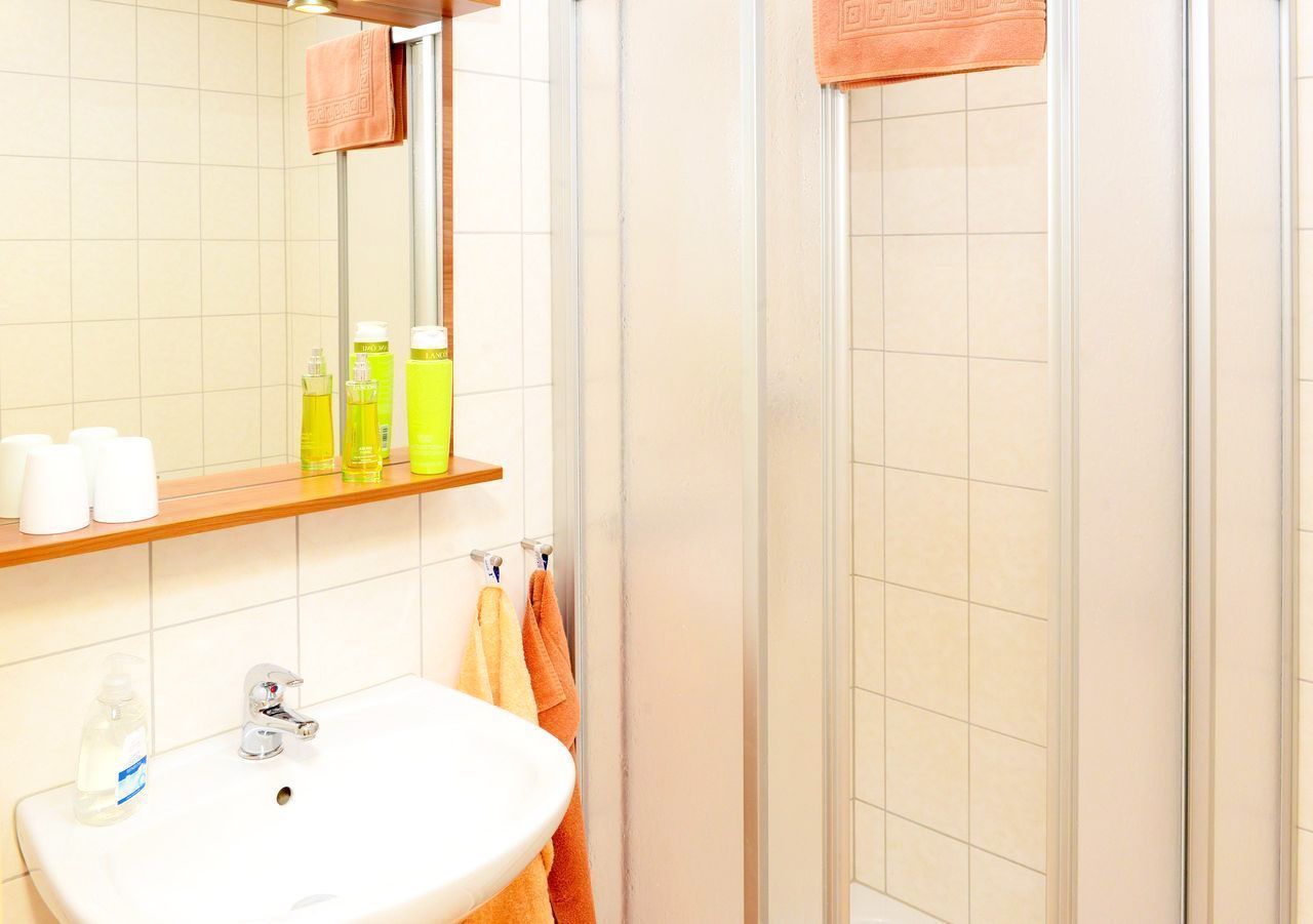 A bathroom with a sink, mirror, and shower.