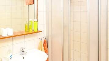 A bathroom with a sink, mirror, and shower.
