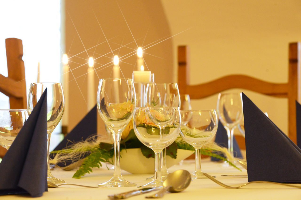 Uma mesa posta com taças de vinho, uma vela e um arranjo de flores.