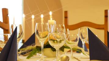 Uma mesa posta com taças de vinho, uma vela e um arranjo de flores.