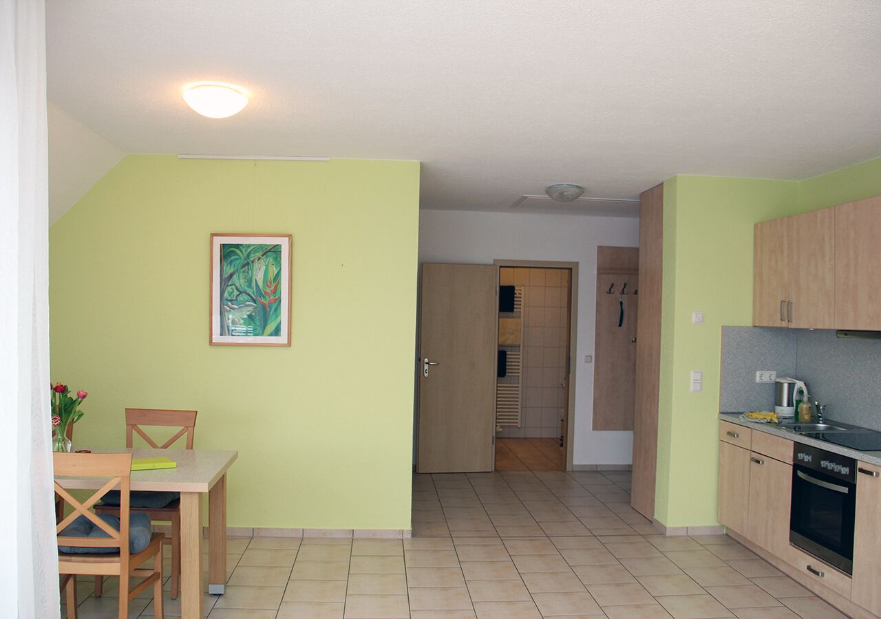 Una cocina compacta con comedor, una puerta de madera que da a un espacio de almacenamiento y piso de baldosas.