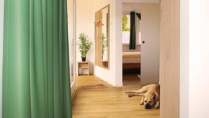 A hallway with a dog lying on the floor, a small table with a plant, and a mirror on the wall.