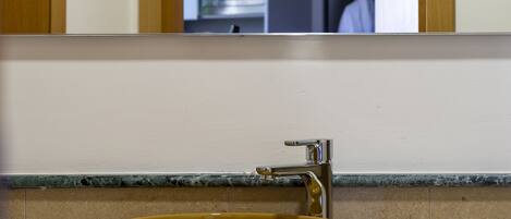 A bathroom with a large yellow sink, a mirror, and a towel on the counter.