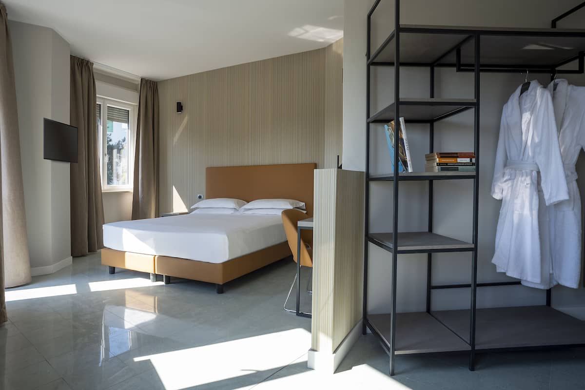Una habitación de hotel moderna con una cama grande, un armario y un televisor de pantalla plana.
