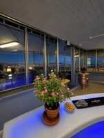 Un interior moderno con ventanas amplias, una planta en maceta y una mesa de exhibición.