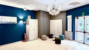 Un vestíbulo moderno con una pared azul, una araña y un extintor.