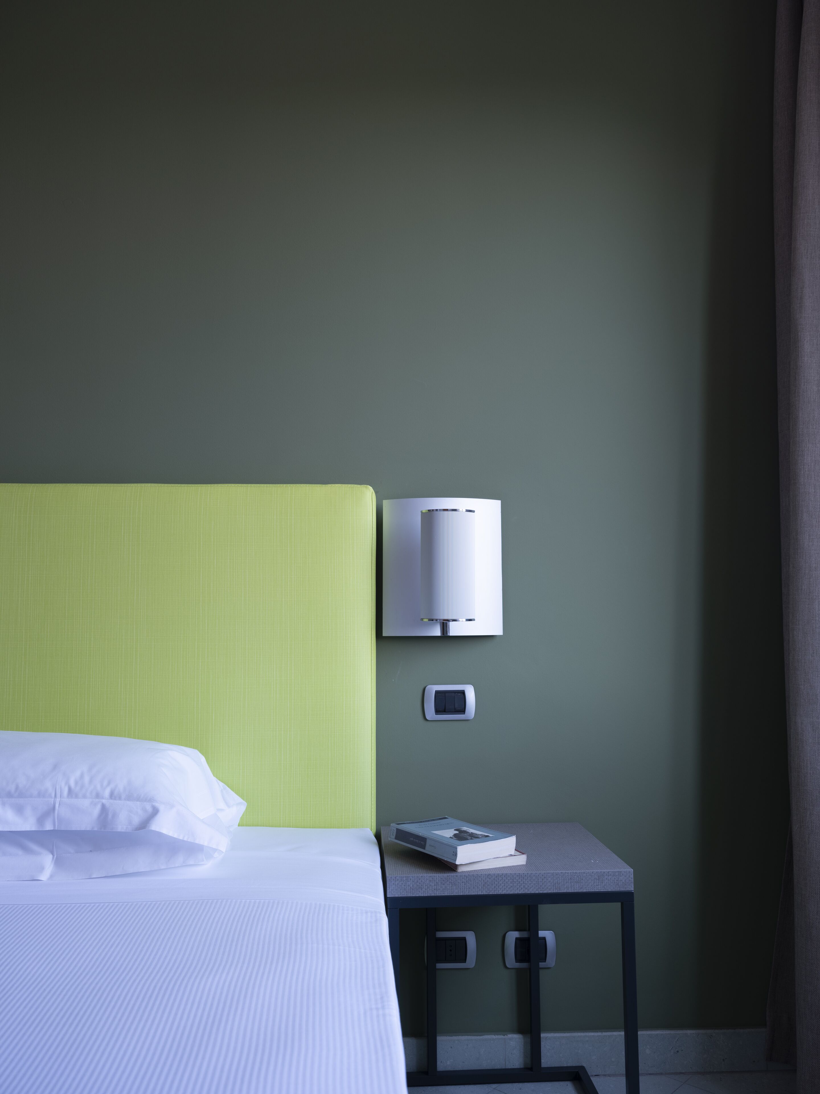 Une chambre d’hôtel avec un lit, une table de chevet avec une lampe et une prise électrique.