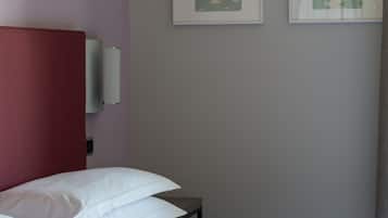 Una habitación de hotel con una cama, un cabecero rojo y dos cuadros en la pared.
