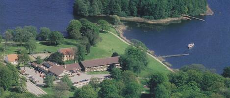 An aerial view of a lakeside property with a large building, a dock, and a boat.